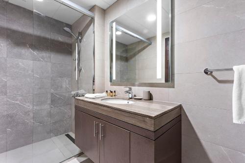 y baño con lavabo, espejo y ducha. en Silkhaus Luxury 1 BDR Close To Reem Central Park en Abu Dabi