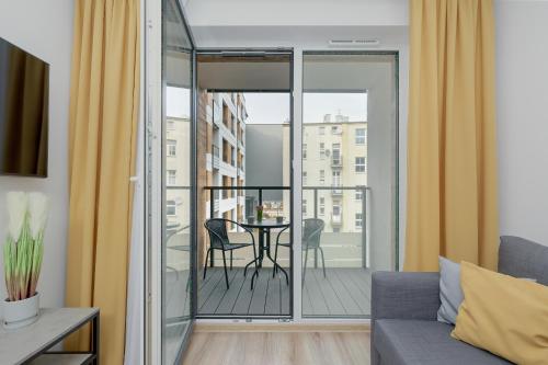 コウォブジェクにあるExclusive and Modern Grey Apartment with Furnished Balcony in Kołobrzeg by Rentersのリビングルーム(テーブルと椅子付きのバルコニー付)