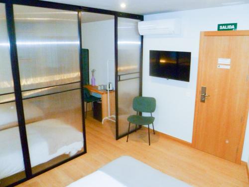 une chambre avec une porte coulissante en verre et une chaise dans l'établissement OLBLANC Plaza de España by Batuecas, à Madrid