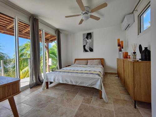a bedroom with a bed and a ceiling fan at Jacuzzi, Sauna, Piscine et Magnifique Vue sur la Mer ! Vivez le Luxe de la Dépendance de la Villa Nadia in Le Diamant