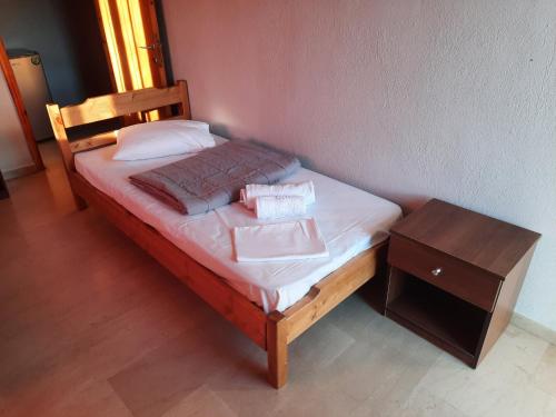 a bed with two pillows and a night stand next to it at CHRISTOS Apartments in Paralia Panteleimonos