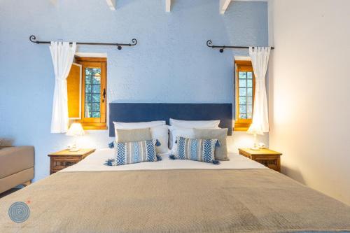 a bedroom with a large bed with blue walls and windows at Abeliona Retreat in Ambeliona