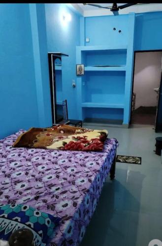 a bedroom with a bed with a purple comforter at Maa Mansha guest house in Deoghar