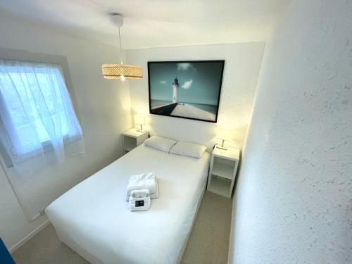 - une chambre avec un lit blanc et une télévision murale dans l'établissement PGH N28 - À 200m de la Plage avec Parking Privé, à La Grande Motte