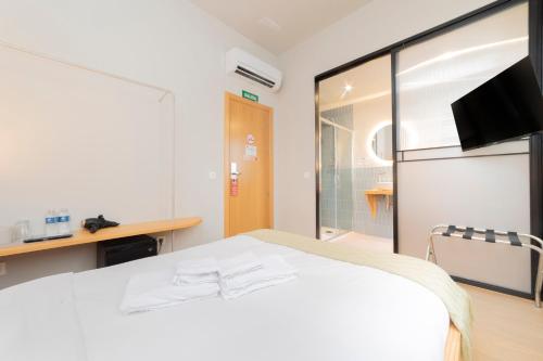 a bedroom with a white bed and a tv at OLBLANC Plaza de España by Batuecas in Madrid