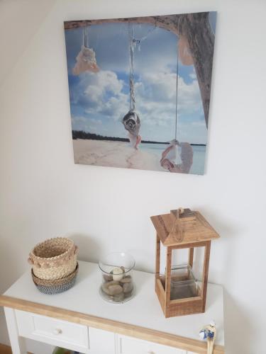 einen Tisch mit einem Bild vom Strand und einer Vogelschaukel in der Unterkunft CHAMBRE LIT DOUBLE A proximité de Paris in Champagne-sur-Oise