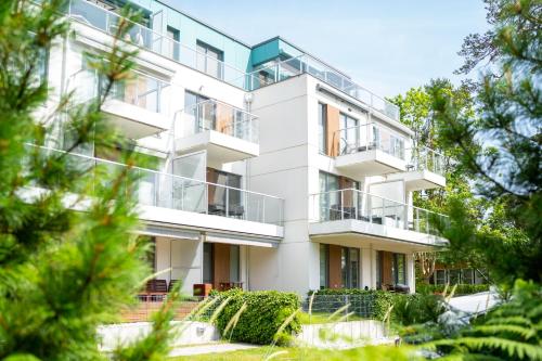 an apartment building with balconies and trees at Apartamenty In Mestwina 37 Jurata in Jurata