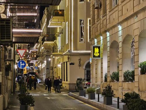 un grupo de personas caminando por una calle por la noche en Haz Boutique Hotel Baku en Bakú