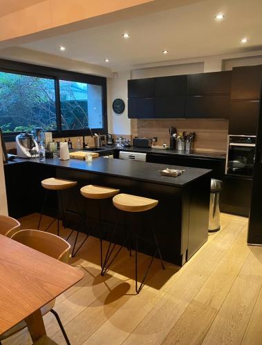 une cuisine avec un grand îlot et des tabourets de bar dans l'établissement Appartement Design avec Jardin 4 pers 2 Chambres, à Paris