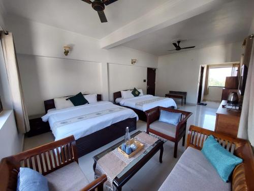 a hotel room with two beds and a table and chairs at Alinda House Naukuchiatal by THE GHAUR in Bhīm Tāl