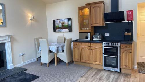 a kitchen with wooden cabinets and a table with chairs at midsummer cottage in Kirby Misperton
