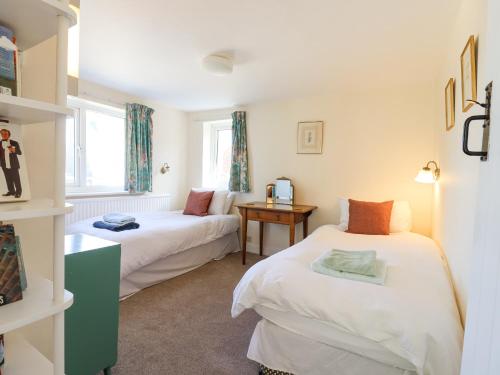 two beds in a room with two windows at Ivy Cottage in West Mersea