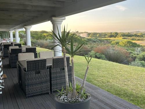 a porch with wicker chairs and a palm tree at St Francis Golf Lodge in St Francis Bay
