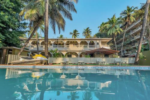 a resort with a swimming pool and palm trees at Rosa Bella Resort-TBV in Calangute