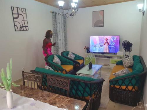 a living room with two couches and a tv at Village des Aviateurs in Nkolnda