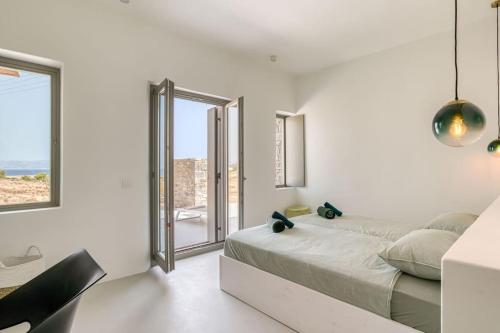 biała sypialnia z łóżkiem i dużym oknem w obiekcie Villa Ena - Beach getaway w mieście Logaras