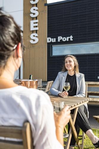 a woman sitting at a table with a glass of wine at Les Terrasses du Port in Saint-Pierre