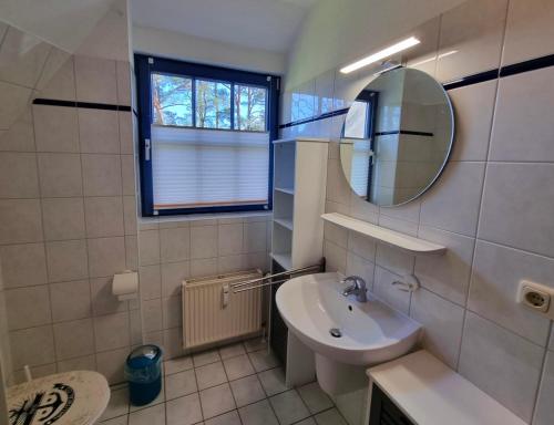 Baño blanco con lavabo y espejo en Ferienwohnung Seeigel en Prerow