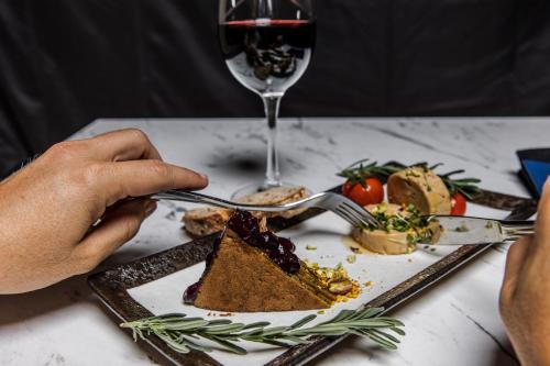 a person eating a plate of food with a glass of wine at Les Terrasses du Port in Saint-Pierre