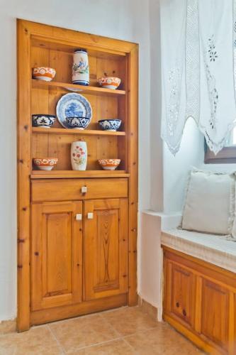 a wooden hutch with bowls and dishes on it at Olia Cottage in Karpathos