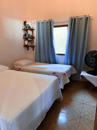 um quarto com duas camas com cortinas azuis e uma janela em Casa conforto em Pirenópolis