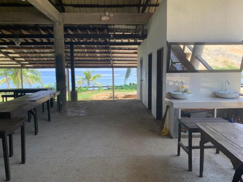 an empty restaurant with tables and a view of the ocean at Villa Malinao Oceanview Resort - Deluxe bungalow in Burgos