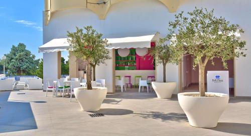 a patio with white tables and chairs and trees at Park Plaza Histria Pula in Pula