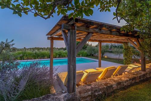 a group of chairs under a pergola next to a swimming pool at Charlotta in Radovani