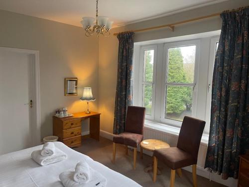 a bedroom with a bed and two chairs and a window at The Westminster Hotel in Buxton