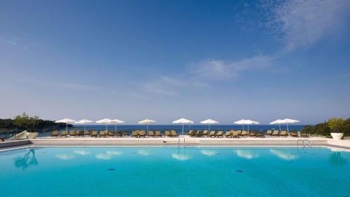 ein großer Pool mit Stühlen und Sonnenschirmen in der Unterkunft Park Plaza Verudela Pula in Pula