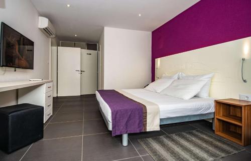 a hotel room with a bed and a purple wall at Park Plaza Verudela Pula in Pula