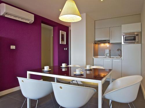 a kitchen with purple walls and a table and chairs at Park Plaza Verudela Pula in Pula