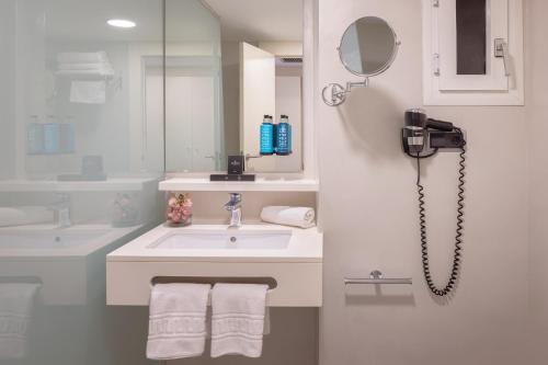 a white bathroom with a sink and a phone at Calipolis in Sitges