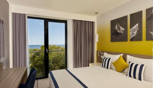 a hotel room with a bed and a desk and a window at Park Plaza Arena Pula in Pula