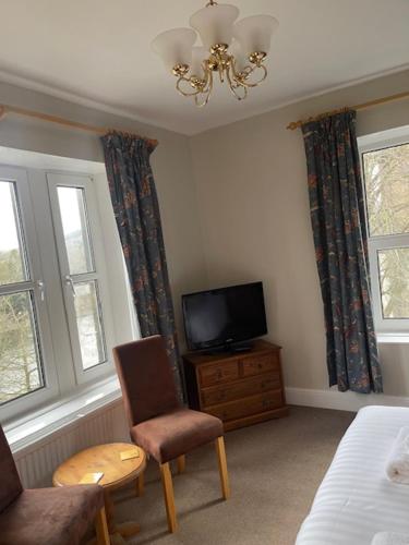 a bedroom with a tv and a chair and a bed at The Westminster Hotel in Buxton