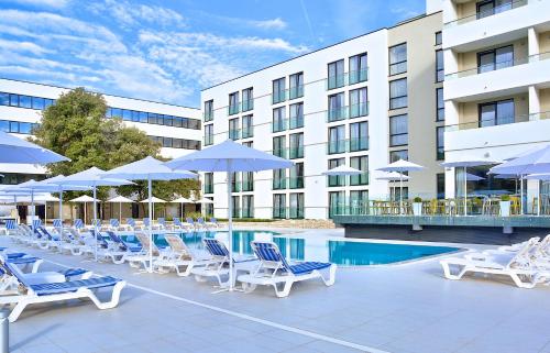 a pool with chairs and umbrellas next to a hotel at Park Plaza Arena Pula in Pula