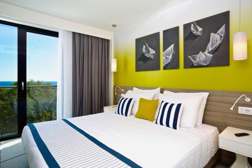 a bedroom with a bed with yellow walls and a window at Park Plaza Arena Pula in Pula