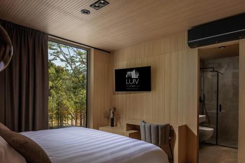 a bedroom with a bed and a bathroom with a window at Villa Luiv Chalet in Mrkopalj