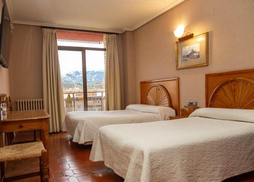 una camera d'albergo con due letti e una finestra di HOSTAL DOÑA JUANA ad Ágreda
