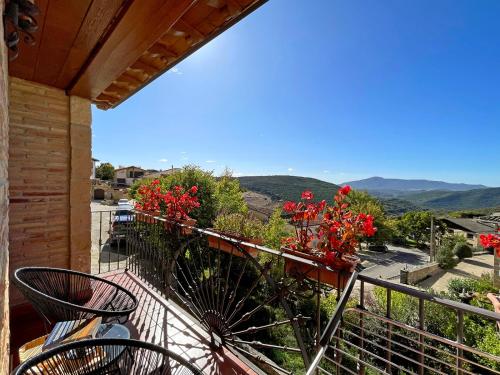 a balcony with two chairs and red flowers on it at Casar Rural Lazkua I-II in Eraul
