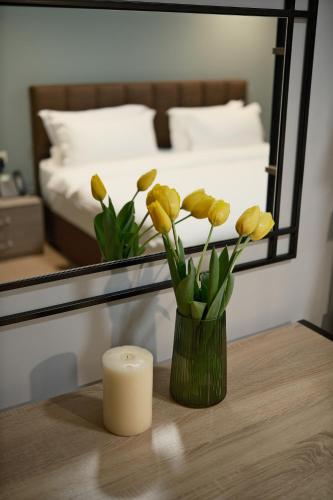 a vase of yellow flowers on a table with a candle at Felinger Concept Hotel in Yerevan