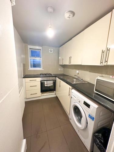 een kleine keuken met een wasmachine en droger. bij Fernandos Flats! Stunning Soho Apartments, meters from Piccadilly Circus, 2 Beds in Londen
