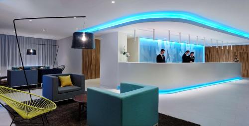 a lobby with a blue lighted mirror and chairs at Park Plaza Belvedere Medulin in Medulin