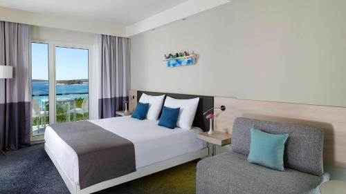 a hotel room with a bed and a chair at Park Plaza Belvedere Medulin in Medulin