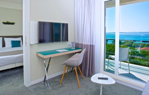 a bedroom with a desk with a television and a window at Park Plaza Belvedere Medulin in Medulin
