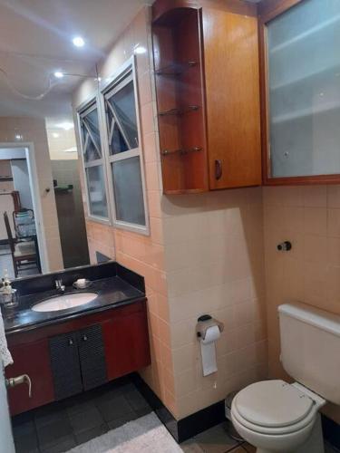 a bathroom with a toilet and a sink and a mirror at Apart na Praia do canto in Vitória
