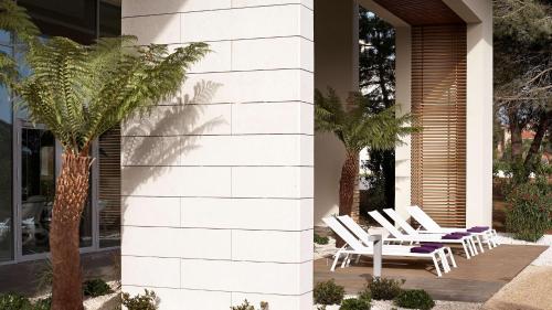 a group of white chairs on a patio with palm trees at Park Plaza Belvedere Medulin in Medulin