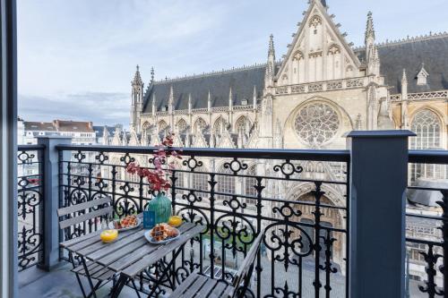 uma varanda com uma mesa com comida e uma igreja em Sweet Inn - Regence em Bruxelas