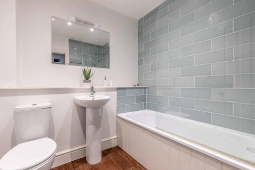 a bathroom with a toilet and a tub and a sink at Cosy Central Windsor Apartment , Parking in Windsor