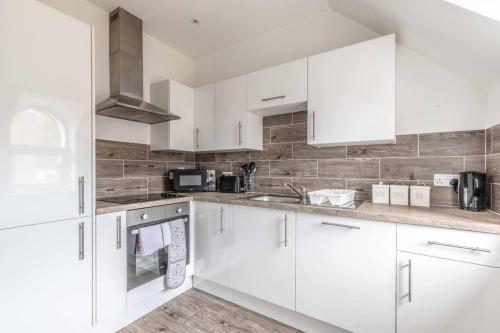 a white kitchen with white cabinets and a sink at Cosy Central Windsor Apartment , Parking in Windsor